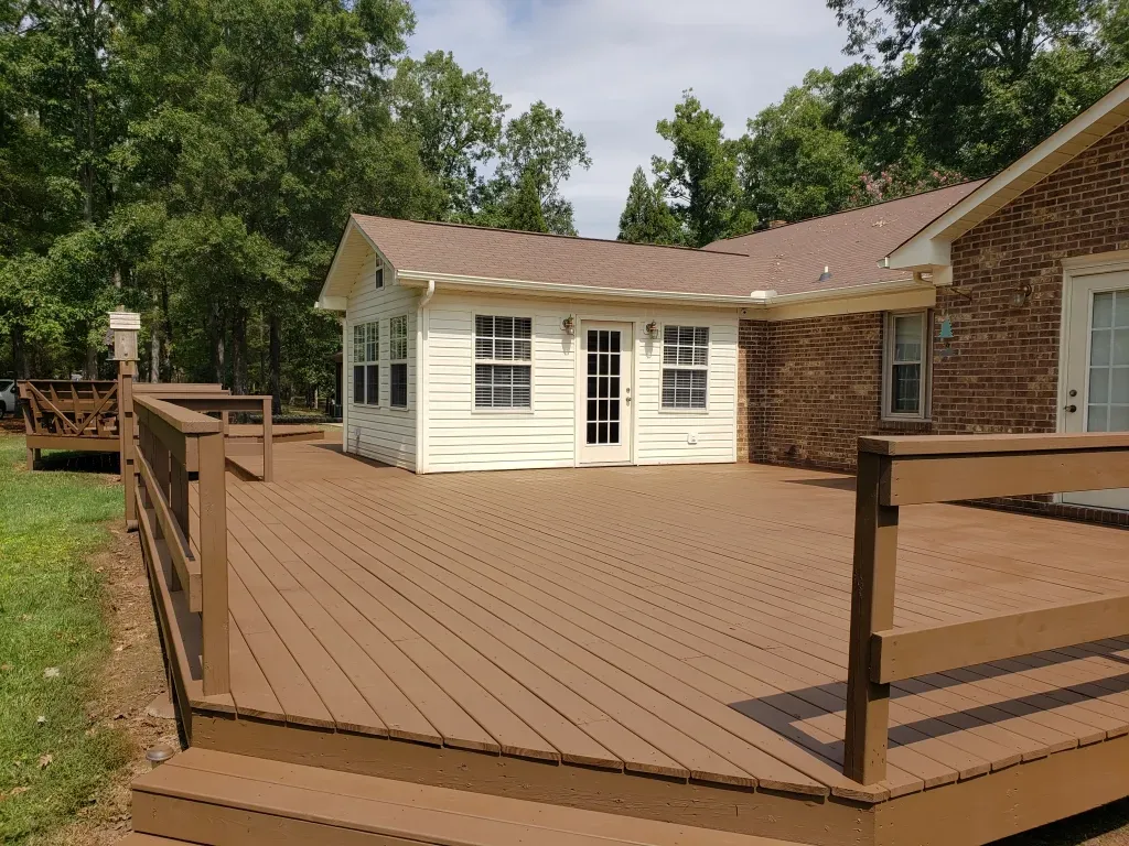 A white house with a brown deck in front of it