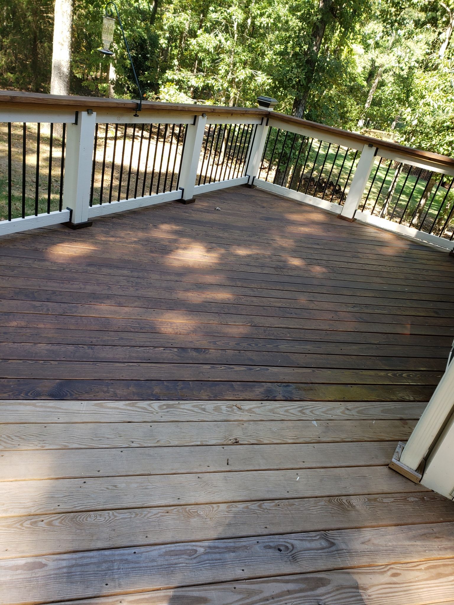A wooden deck with a white railing and trees in the background.