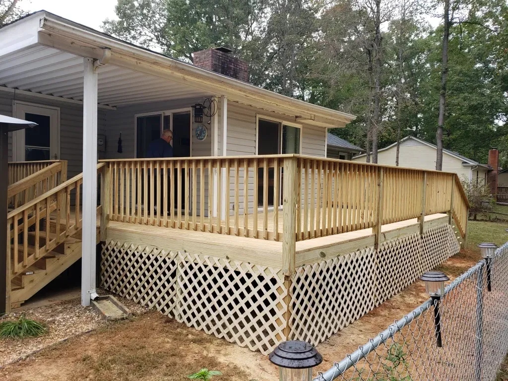 A house with a wooden deck and stairs in front of it.