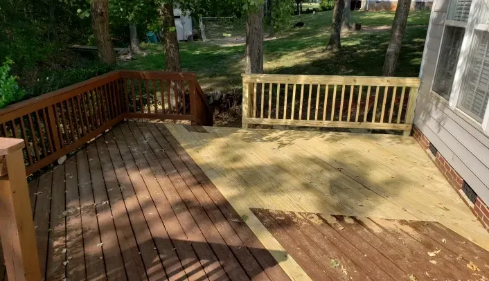 A wooden deck with a wooden railing in the backyard of a house.