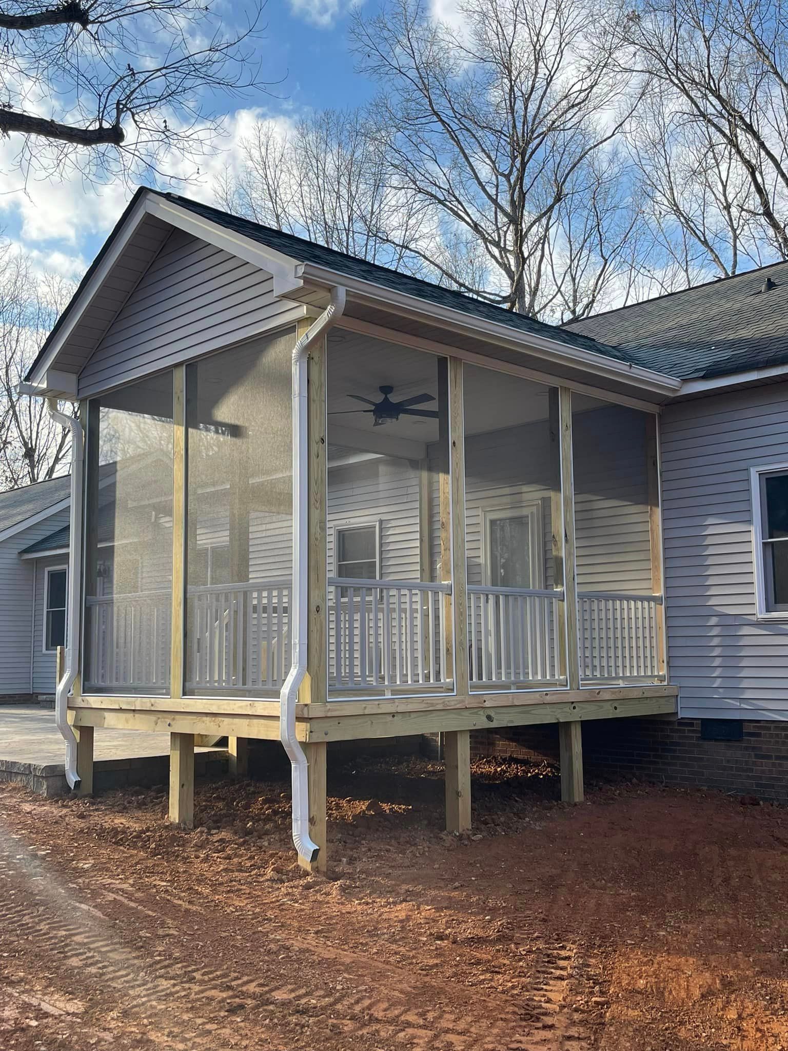 A screened in porch on the side of a house.