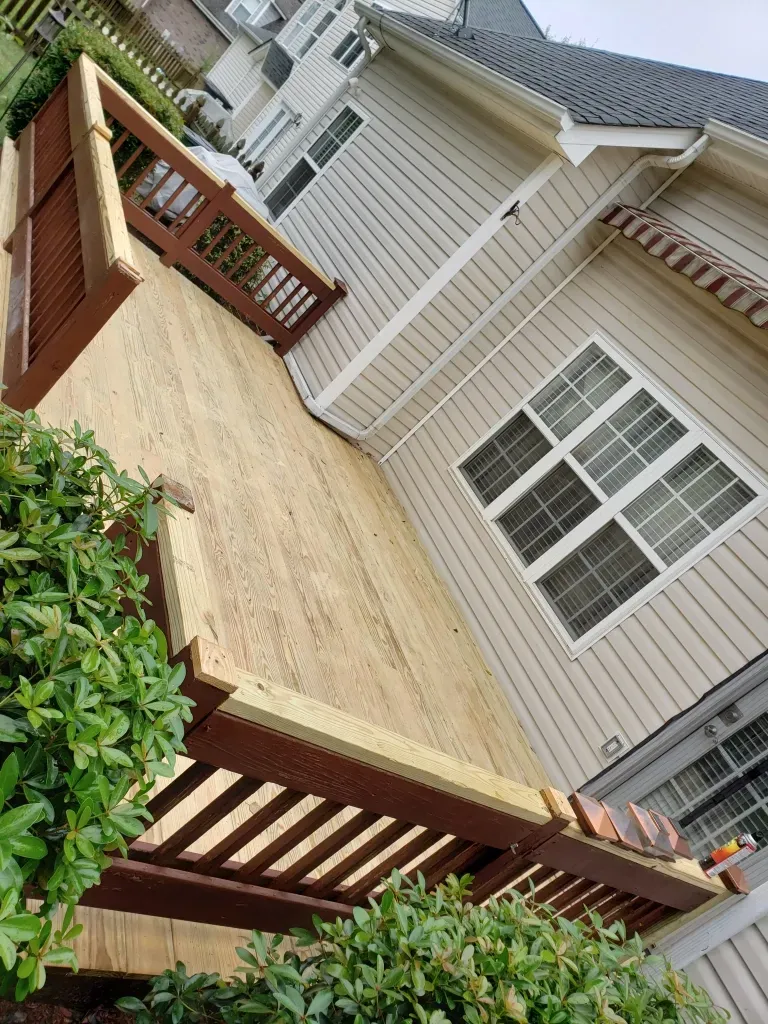 A wooden deck is sitting in front of a house.