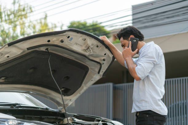 A man is calling a towing service due to a car breakdown.