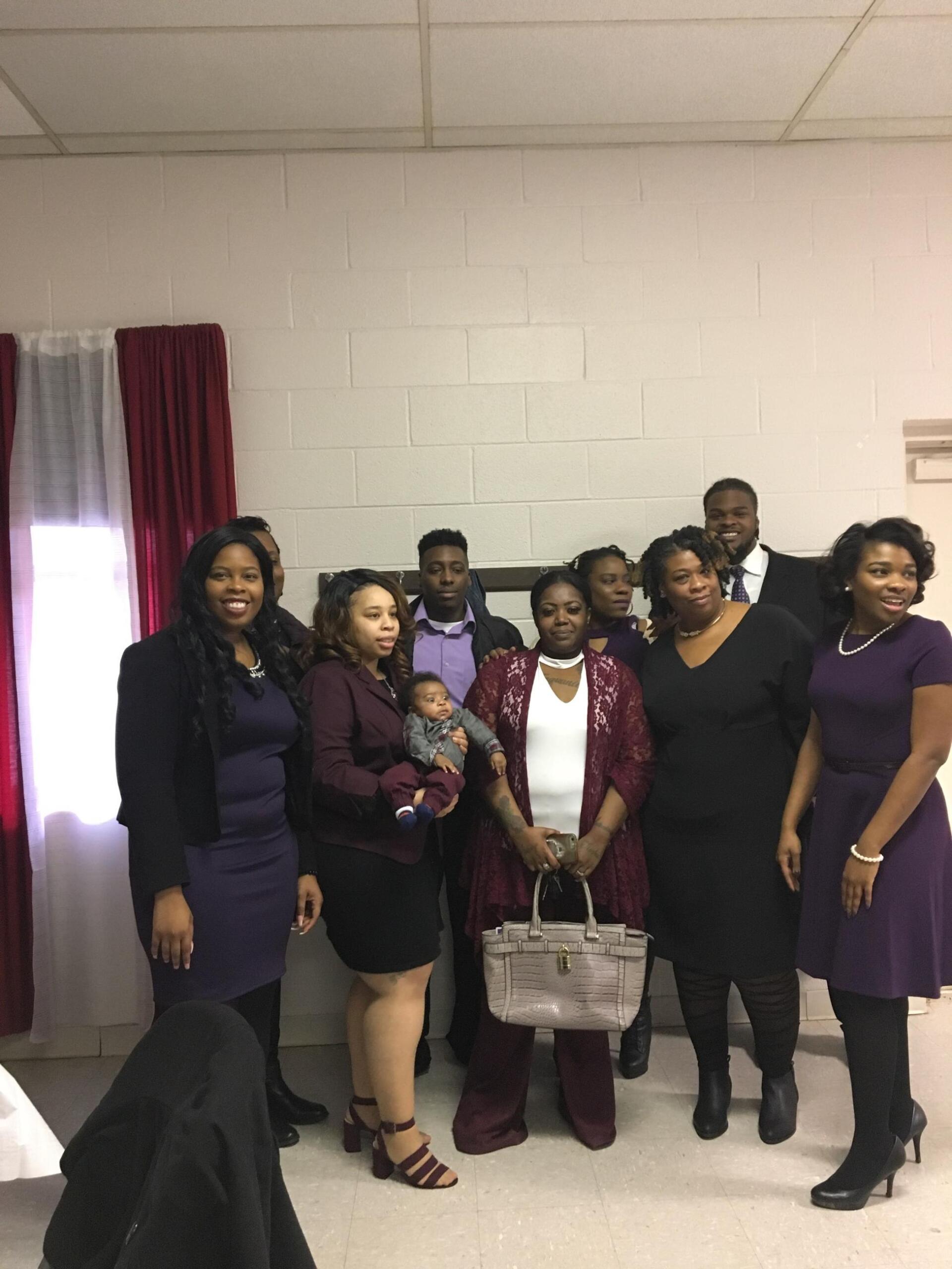 Group of people in formal attire pose inside a room.