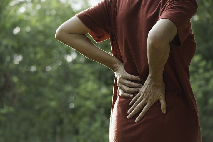 Closeup hands of woman touching her back pain