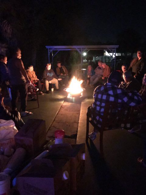 a group of people are sitting around a fire pit and one of them is wearing a shirt that says peace
