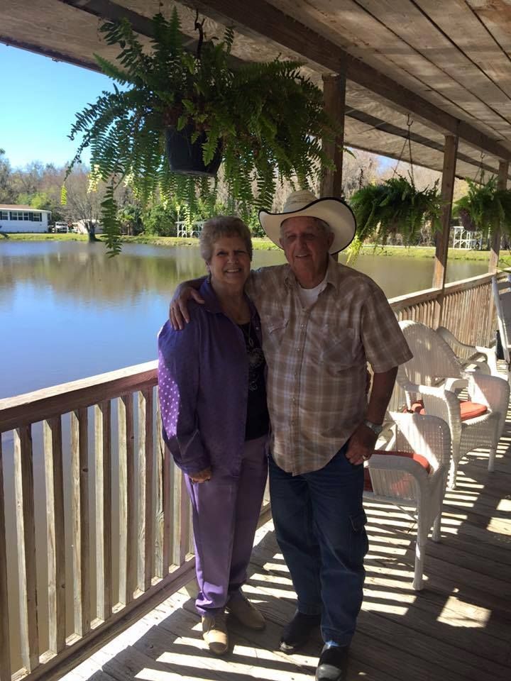 a man in a cowboy hat stands next to a woman on a porch