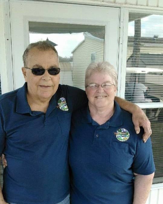 a man and a woman are posing for a picture in front of a window .
