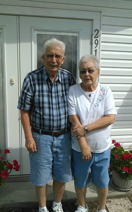 a man and woman standing in front of a house with the number 291 on the door