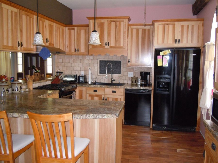 Kitchen with light wood cabinets, granite countertops, and black appliances.