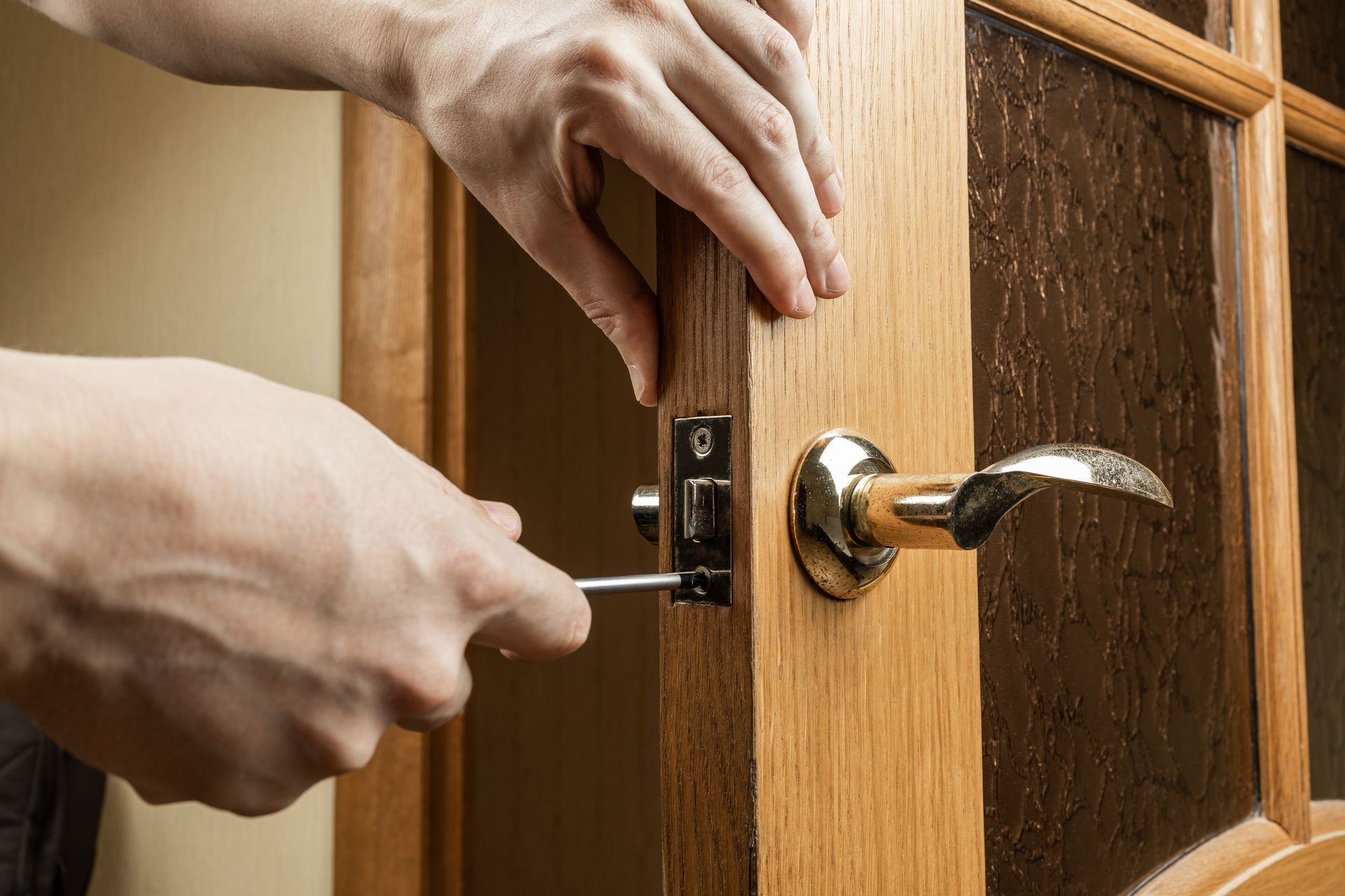 Installer fitting a lever door handle on a wood panel door.