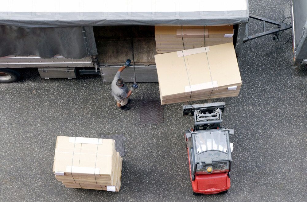 An Aerial View of a Man Loading Boxes Into a Truck — Wide Bay Removals In Dundowran, QLD An aerial view of a man loading boxes into a truck — Wide Bay Removals In Dundowran, QLD
