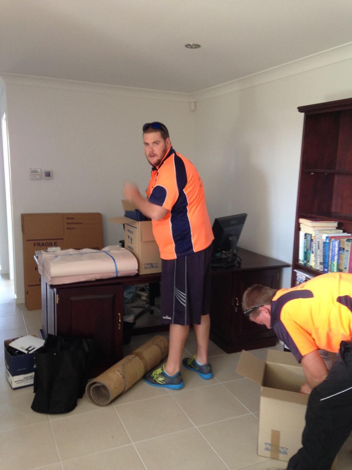 A Man in an Orange Shirt is Standing Next to Another Man — Wide Bay Removals In Dundowran, QLD