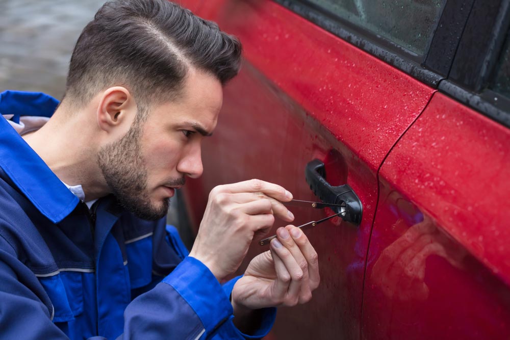 Young Man Opening Red Car Door With Lockpicker — Locksmith In Bendigo, VIC
