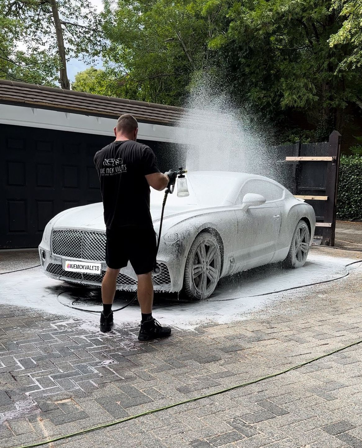 A man is washing a car in a parking lot