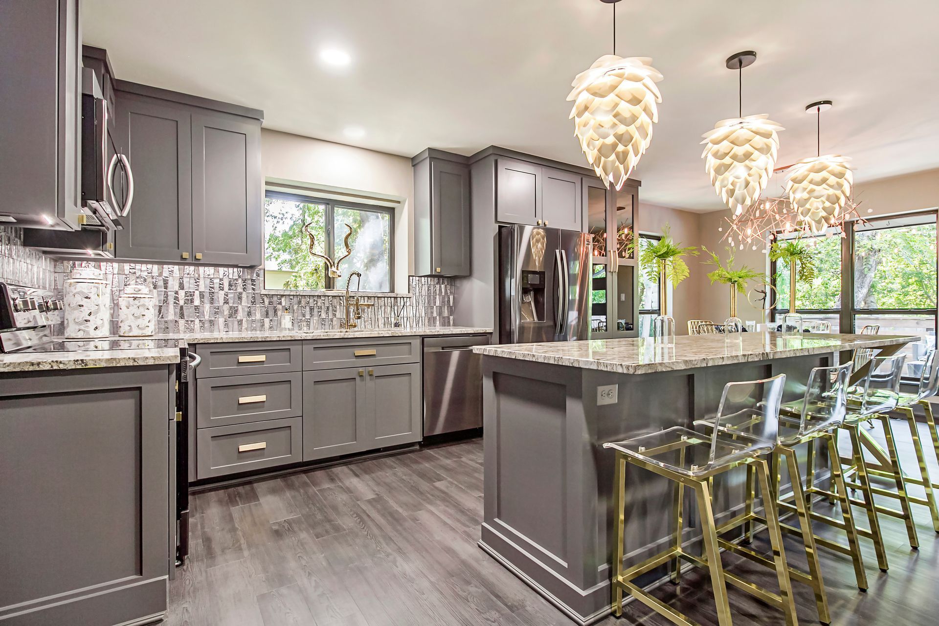 A kitchen with gray cabinets , granite counter tops , stainless steel appliances , and a large island.