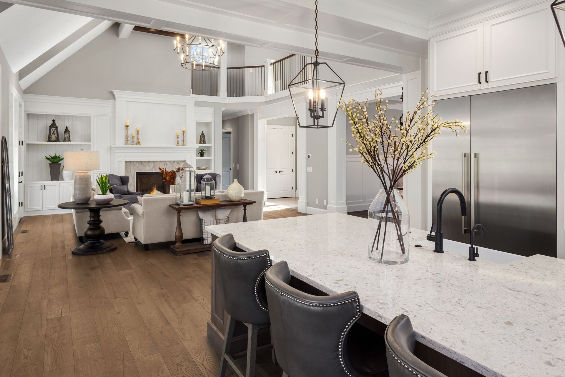 A kitchen with a large island , stainless steel appliances , and a vase of flowers on the counter.