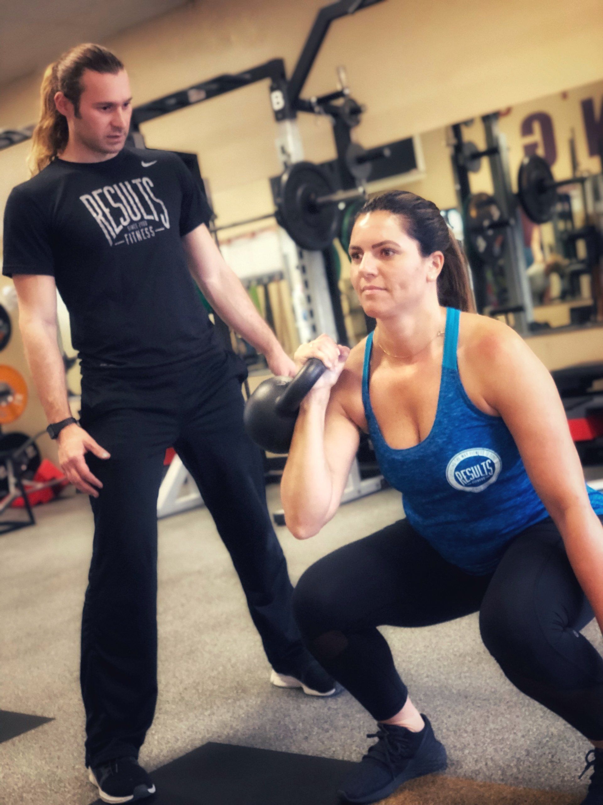 woman doing kettlebell squats with results fitness coach