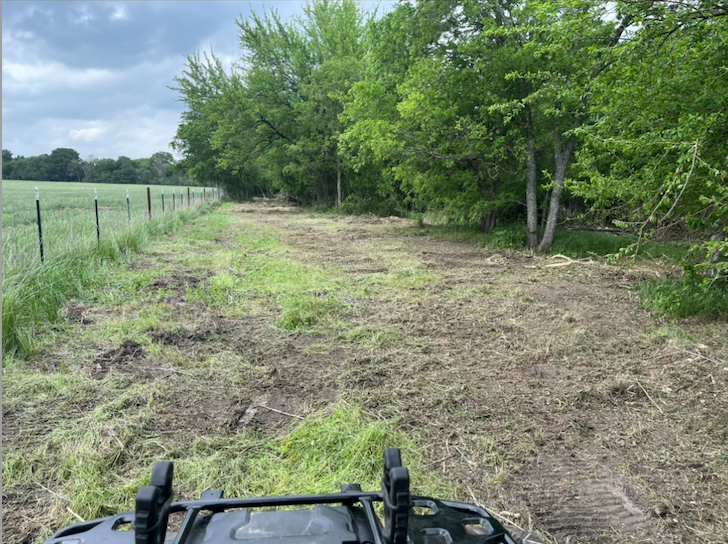 a fence line on a property that has just been cleared with a mulcher