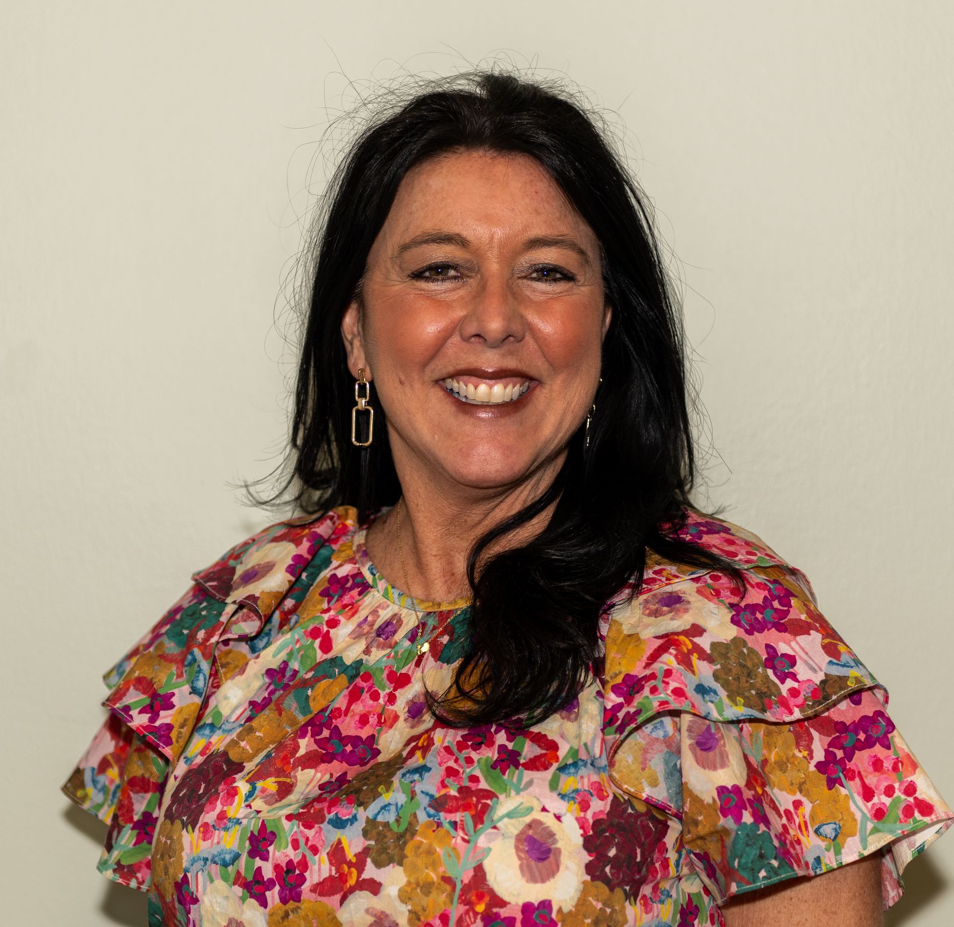 A woman with long hair and a necklace is smiling for the camera.