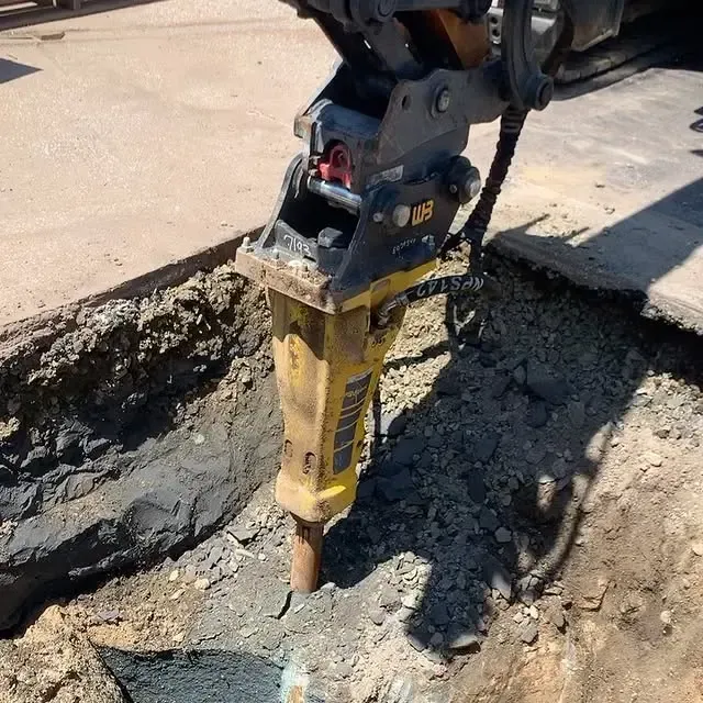 A yellow hammer is being used to dig a hole in the ground