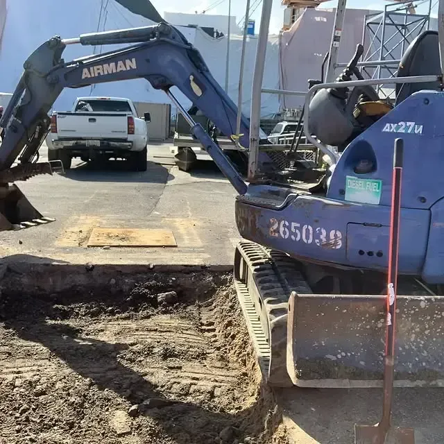 An airman excavator is digging a hole in the ground