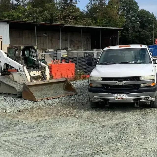 A chevrolet truck is parked next to a bobcat skid steer