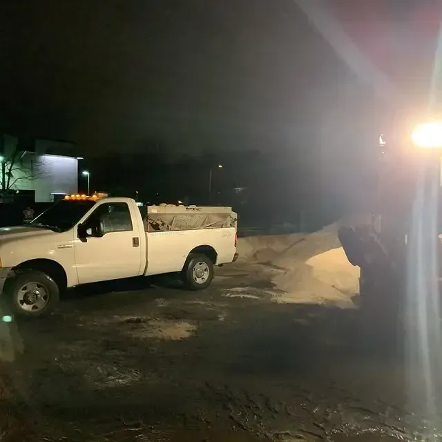 A white truck is parked in a parking lot at night.