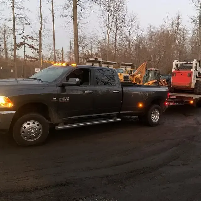 A ram truck is being towed by a bobcat skid steer