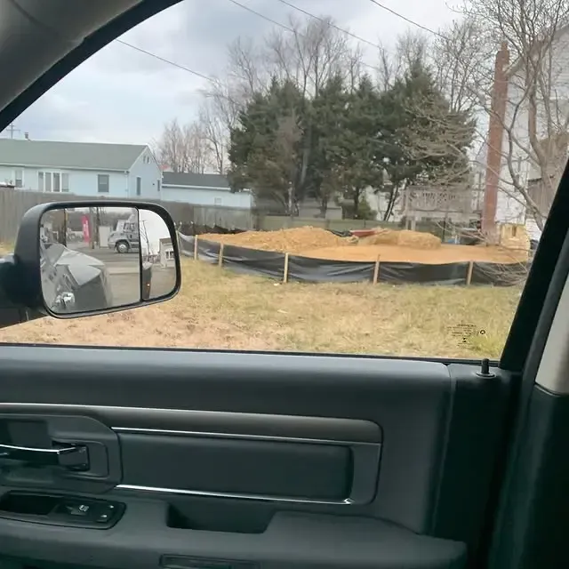 A rear view mirror in a car shows a field of dirt