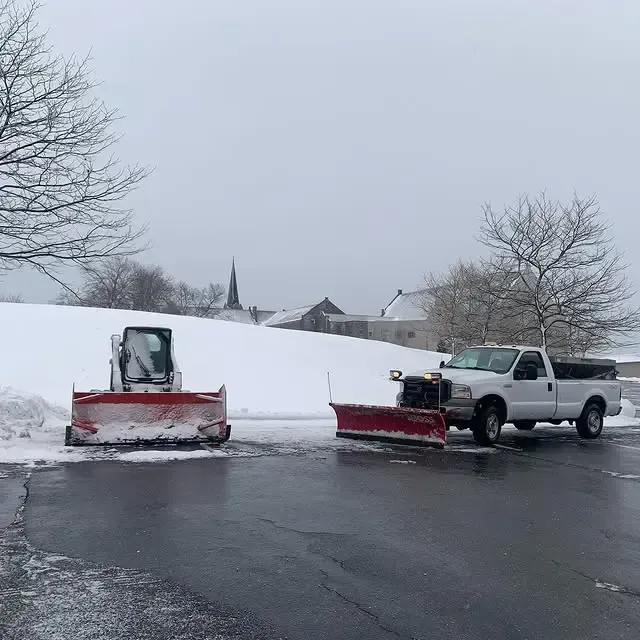 Two snow plows are parked on the side of the road
