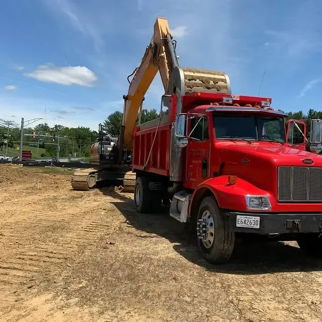 A red dump truck is parked in a dirt field