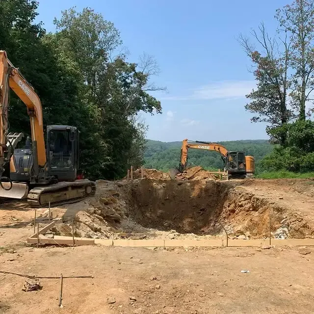 Two excavators are digging a hole in the dirt