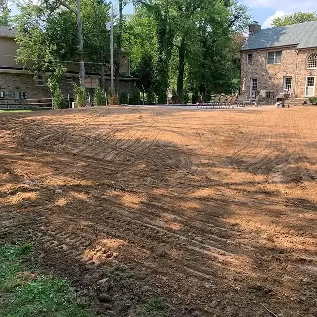 A large dirt field with a house in the background.