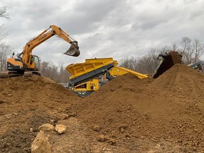 A yellow excavator is loading dirt into a dump truck.