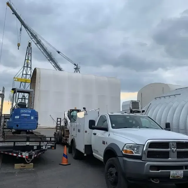 A ram truck is parked next to a crane