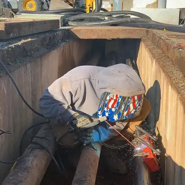A man wearing an american flag hat is welding a pipe