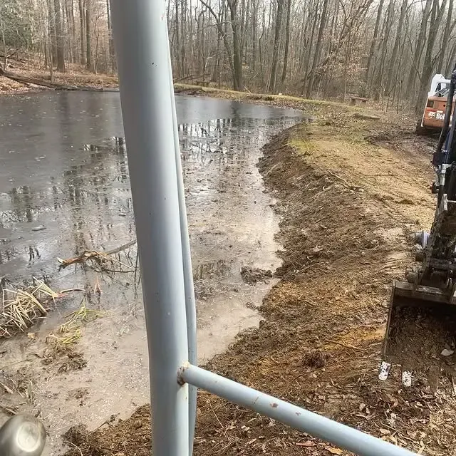 A machine is digging a hole in the ground next to a body of water.