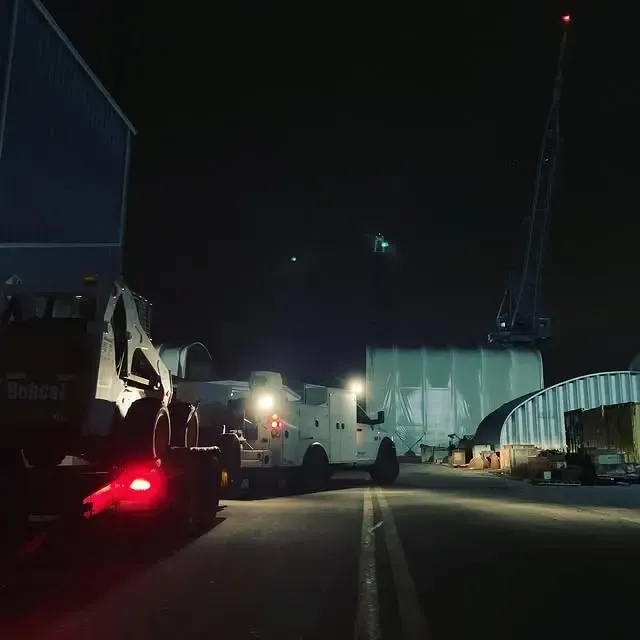 A bobcat truck is parked on the side of the road at night