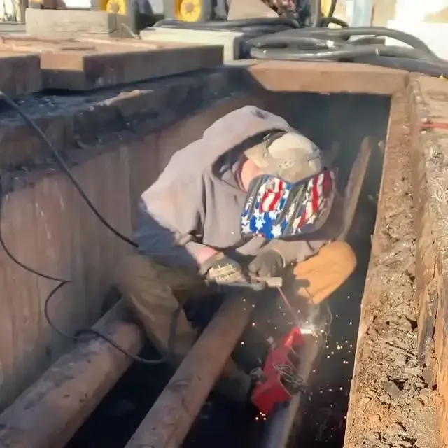 A man wearing an american flag hat is welding a pipe
