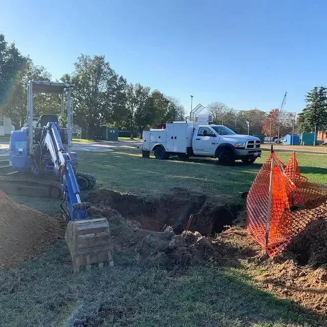A white truck is parked next to a small excavator in a field.