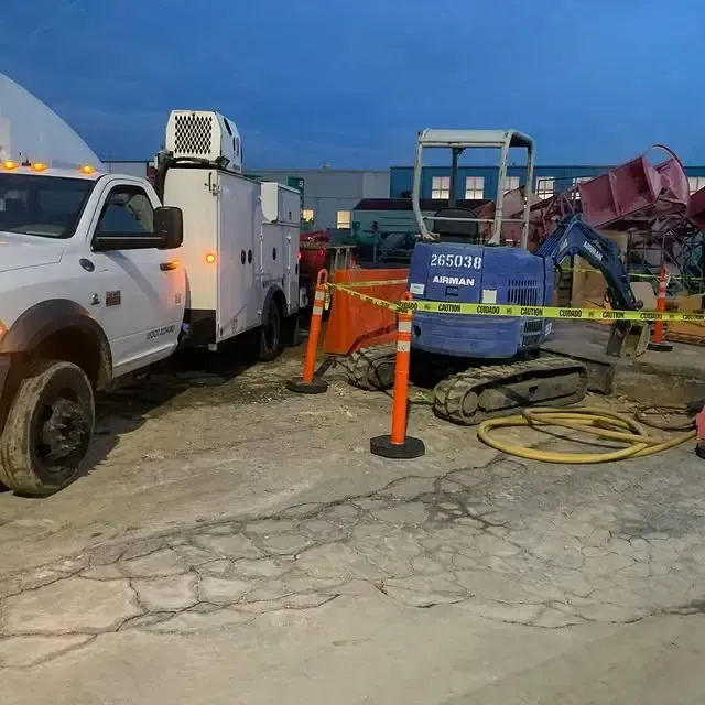 A blue excavator is parked next to a white truck
