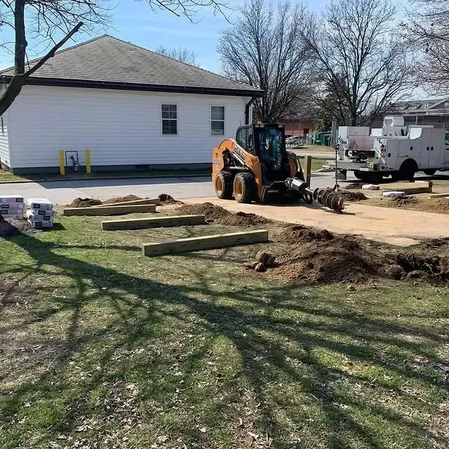 A bulldozer is digging a hole in a yard in front of a house.