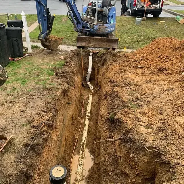 A man is digging a hole in the ground to install a pipe.