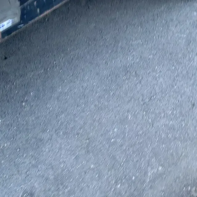 A close up of a gray concrete floor with a few small stones on it.