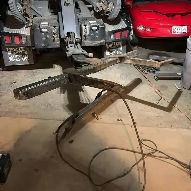 A red car is parked next to a trailer that says west coast