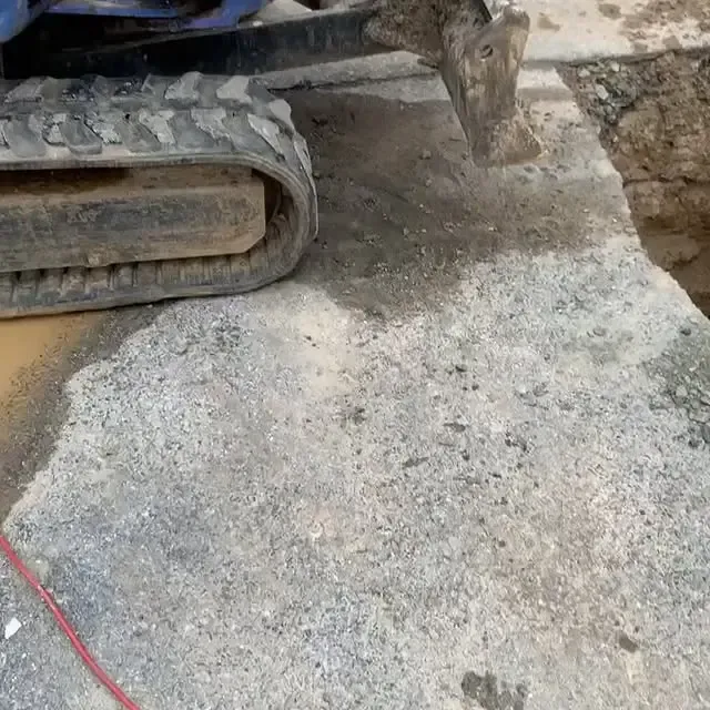 A small excavator is cutting a hole in the ground.