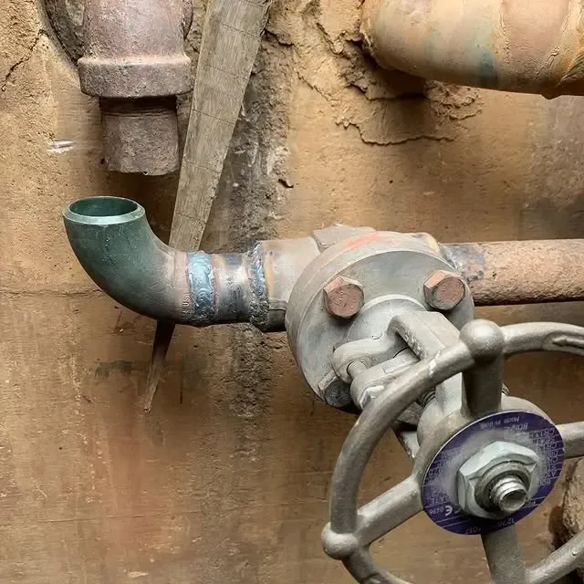 A close up of a valve and pipes on a wall