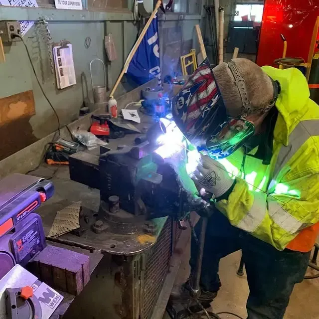 A man wearing a helmet is welding a piece of metal