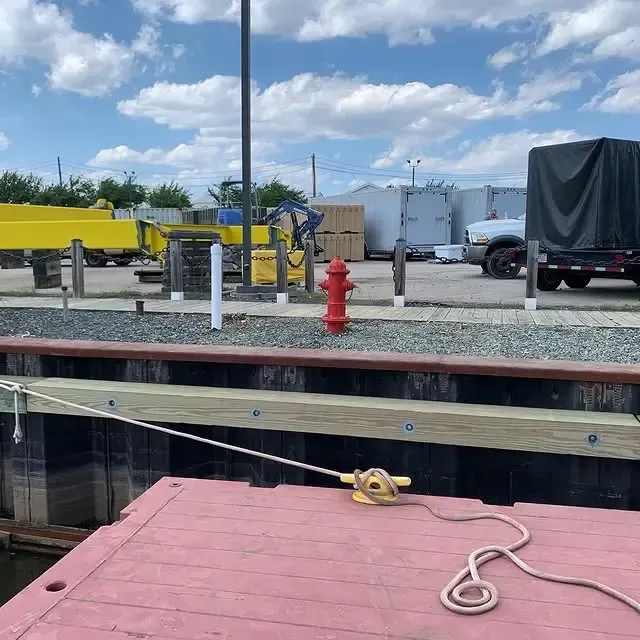 A red fire hydrant is sitting on a dock next to a truck